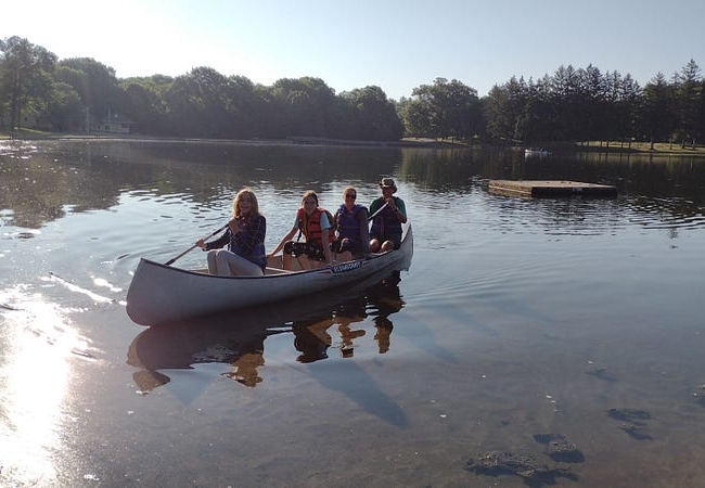 Four people sit in a canoe on the water in Munroe Falls Lake.