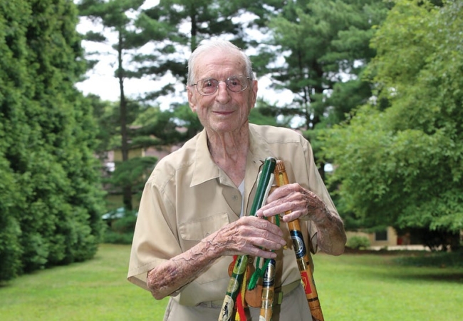 Bert Szabo stands outside with several Fall Hiking Spree staffs in hand.
