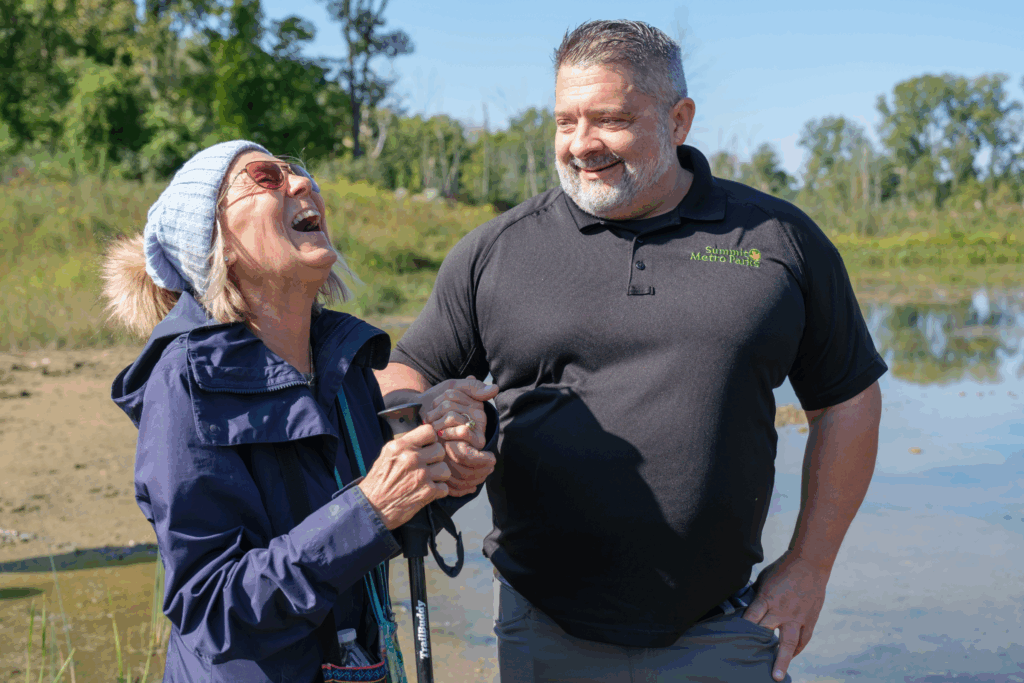 Marilyn Buckey - her head tipped back in laughter - and Mike Johnson, chief of conservation - smiling at Marilyn - share a moment at the Robert A. & Jean C. Meyers Conservation Area to celebrate the success of everyone’s effort to help fulfill SMP’s mission to preserve and conserve our natural resources.