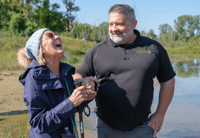 Marilyn Buckey - her head tipped back in laughter - and Mike Johnson, chief of conservation - smiling at Marilyn - share a moment at the Robert A. & Jean C. Meyers Conservation Area to celebrate the success of everyone’s effort to help fulfill SMP’s mission to preserve and conserve our natural resources.