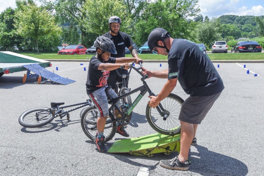 Chris Usner from South Street Ministries Bike Shop helps a child on a bike that's on a small ramp