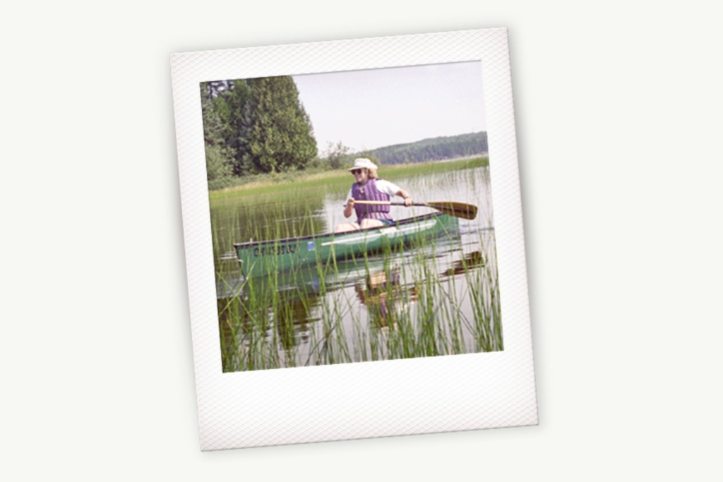 Elaine Marsh paddles a canoe across calm waters on a sunny day