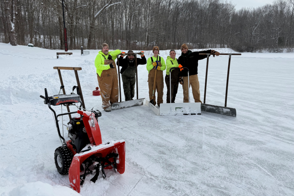 five crew members pose with their snow shovels and snow blower after clearing prepping the ice on Brushwood Lake for ice skating