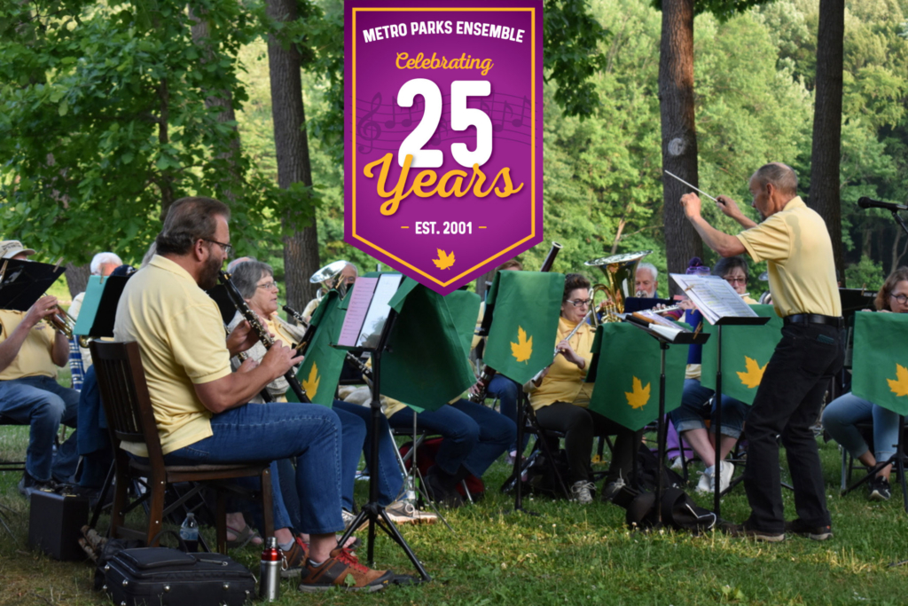 Musicians in yellow shirts sitting while playing instruments with lush greenery in the background. text overlay reads: Metro Parks Ensemble celebrates 25 years, est. 2001