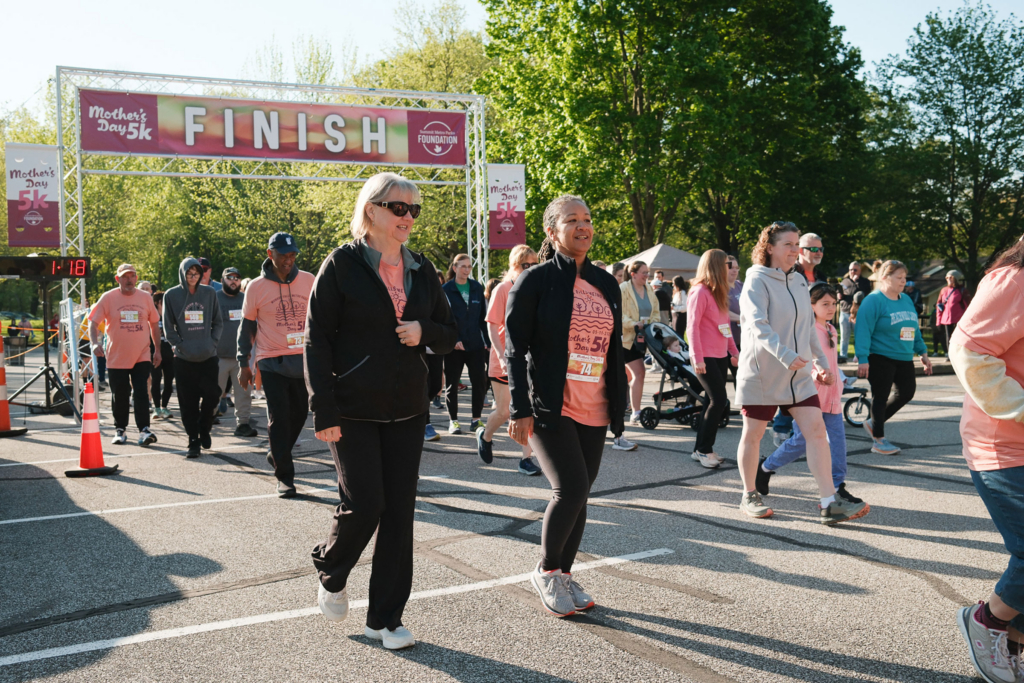 People running and walking on a sunny day with green trees in the background