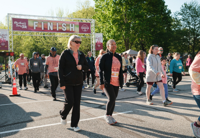 People running and walking on a sunny day with green trees in the background