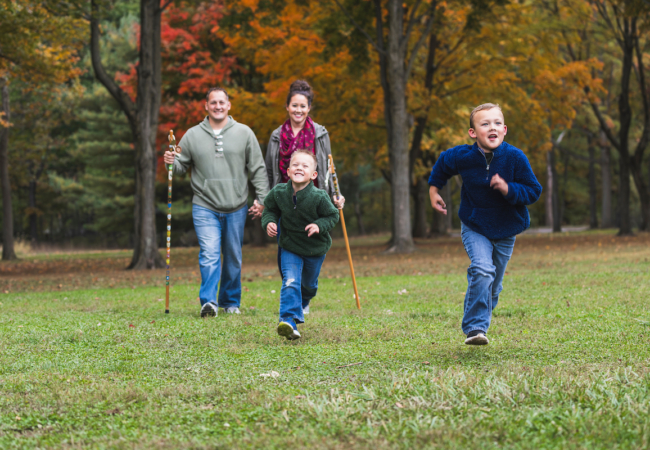 A family of four walks with fall foliage in the background