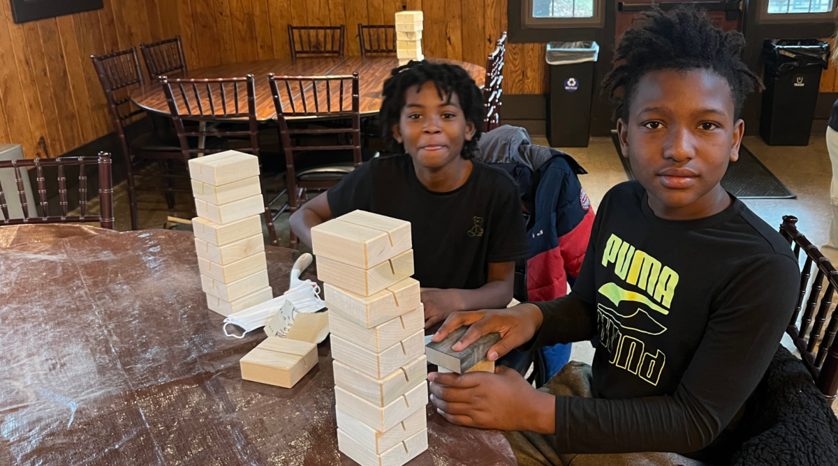 Two students from a local school sanding calendar stands with a stack of finished blocks in front of them
