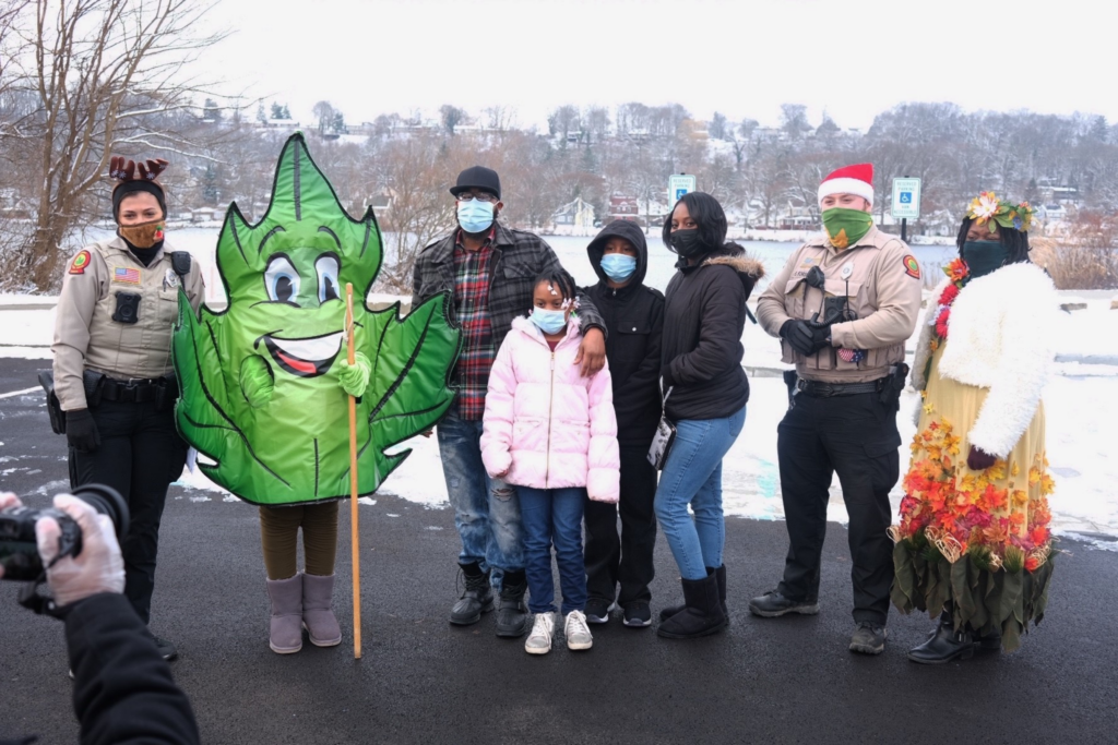 Summit Metro Parks rangers participating in the 2020 Shop with a Cop program stand with a family and Metro Leaf, the park district’s mascot
