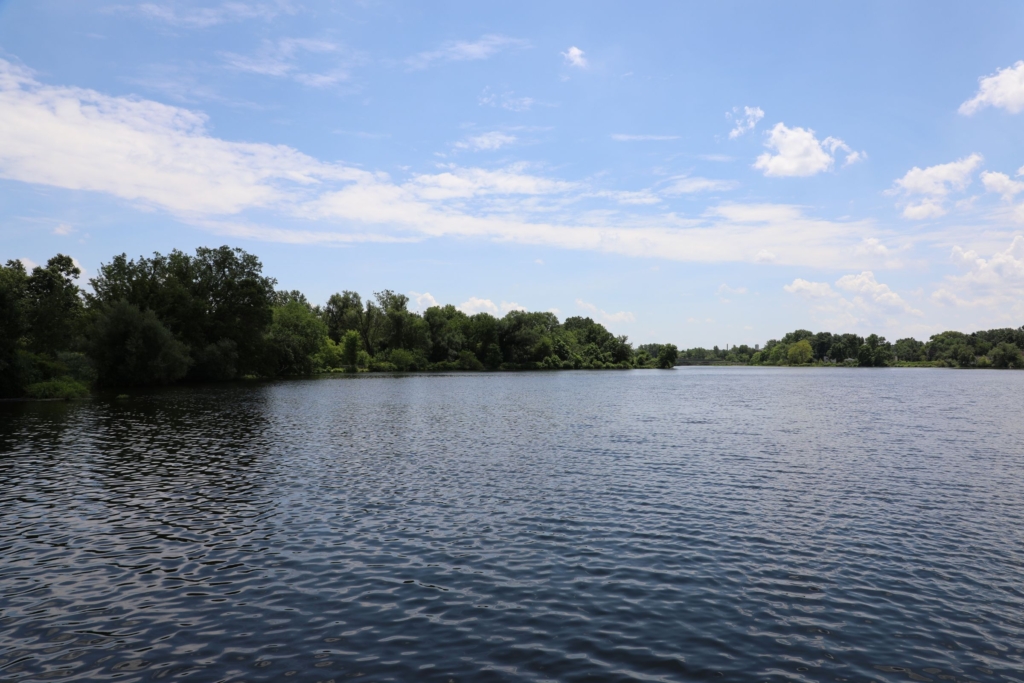 Summit Lake framed by green trees and clouds in a blue sky