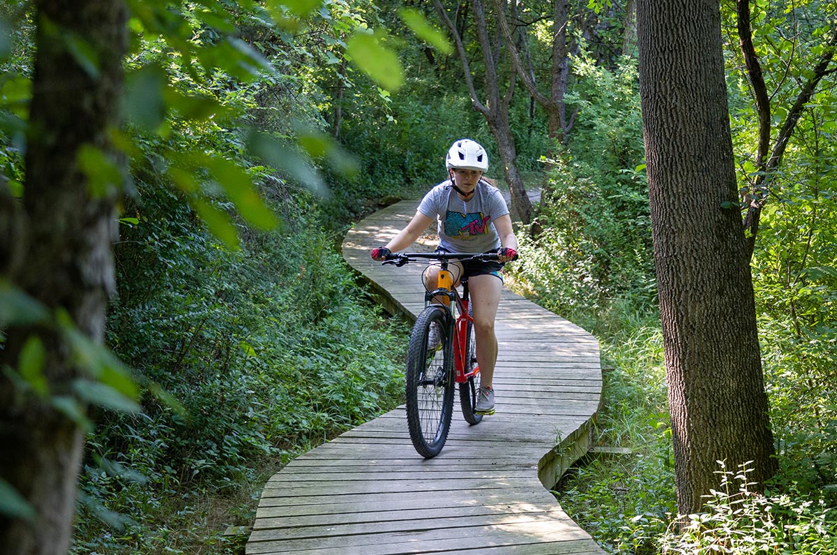 A mountain biker riding along a wooden boardwalk through the woods.