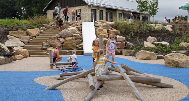 A group of kids plays on a wooden climbing pyramid.