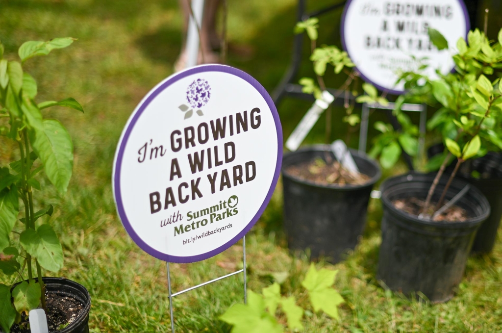a sign that says "I'm Growing a Wild Back Yard with Summit Metro Parks" among plants