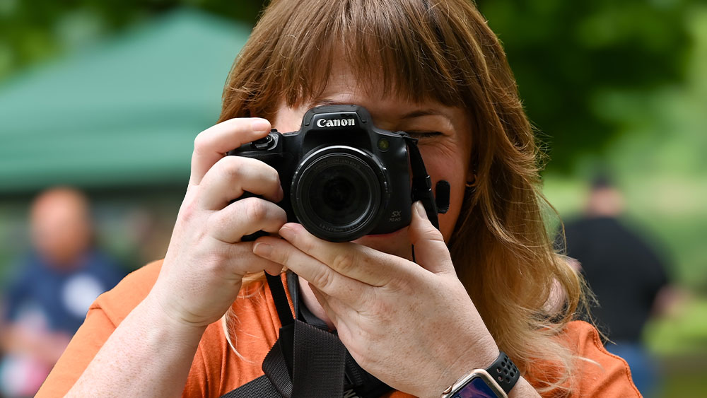 A woman holds a camera up to her face.