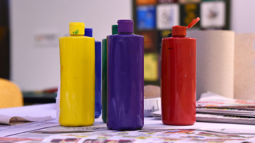 bottles of yellow, blue and red paint sit on a table