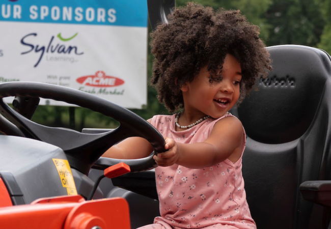 a child sits behind the wheel of a red tractor