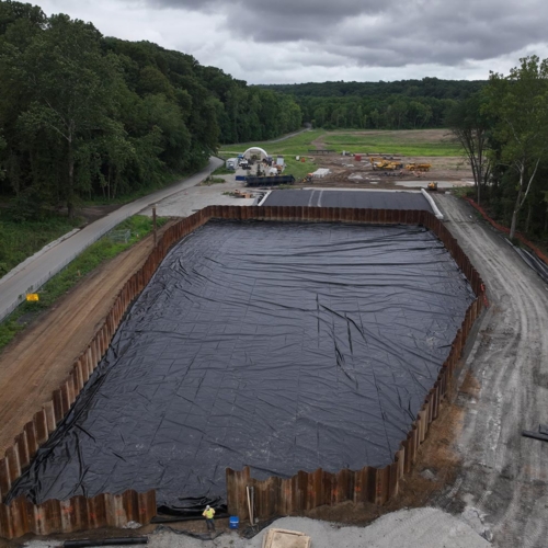 Aerial image of walled-off area with black liner material covering the ground.