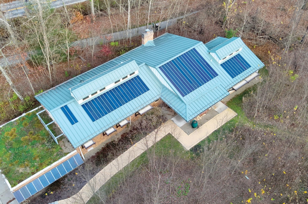 Solar panels atop a building surrounded by woods.
