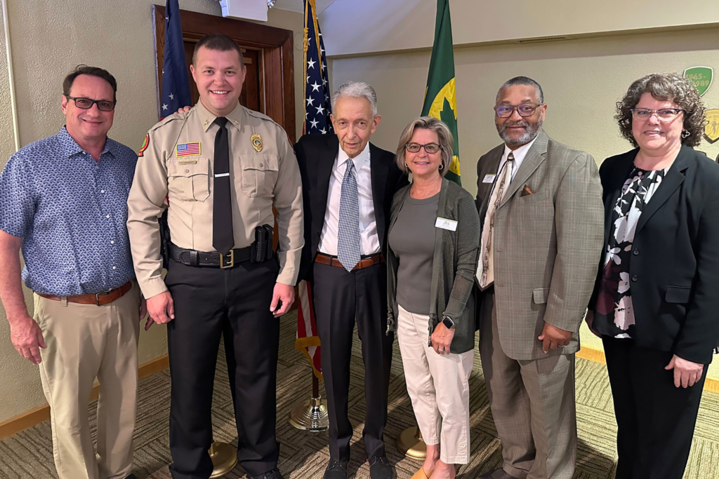 six people stand smiling for a photo, with the american flag and summit metro parks flags in the background