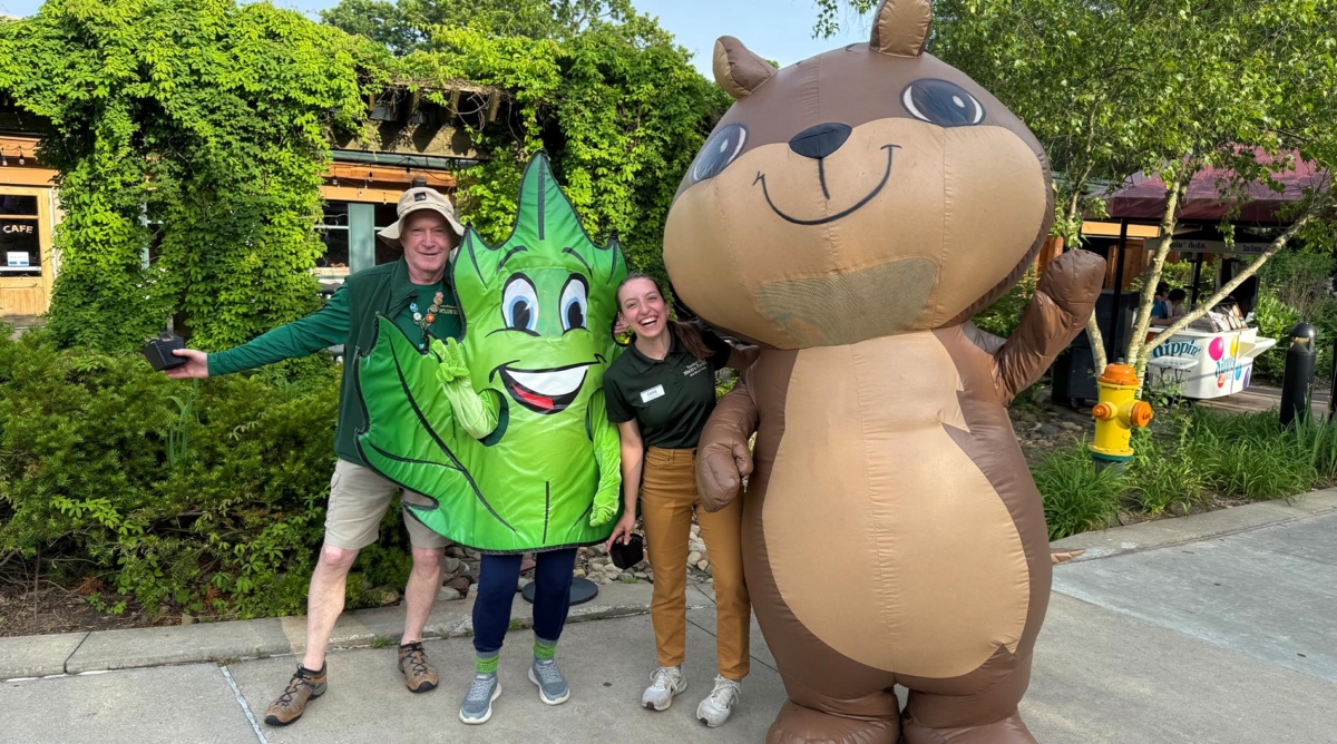 A man and a woman stand with two Summit Metro Parks mascots: Metro Leaf and Cheeks the chipmunk.