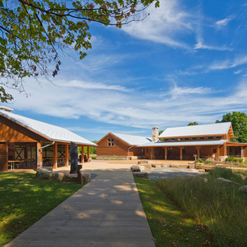A wooden boardwalk leads to a pavilion and building.