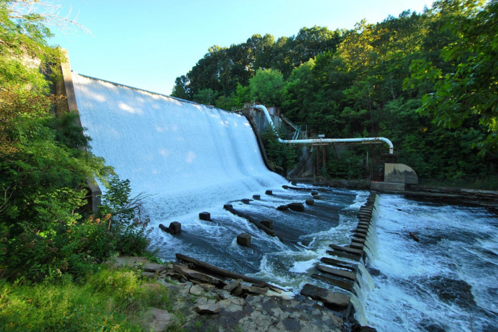 side angle view of water flowing over the damn on a sunny summer day