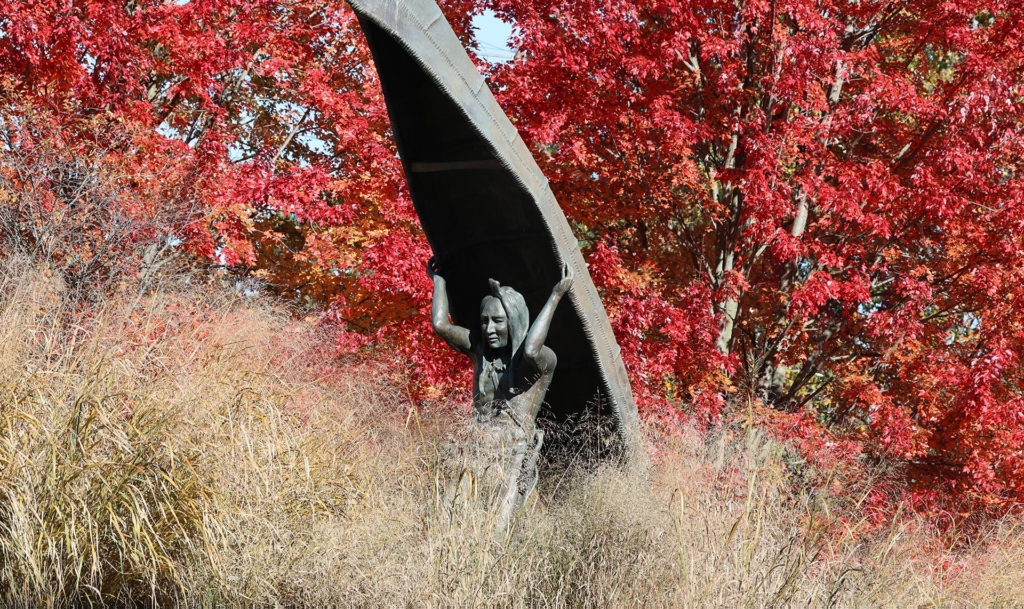 Statue of an American Indian carrying a canoe over his head
