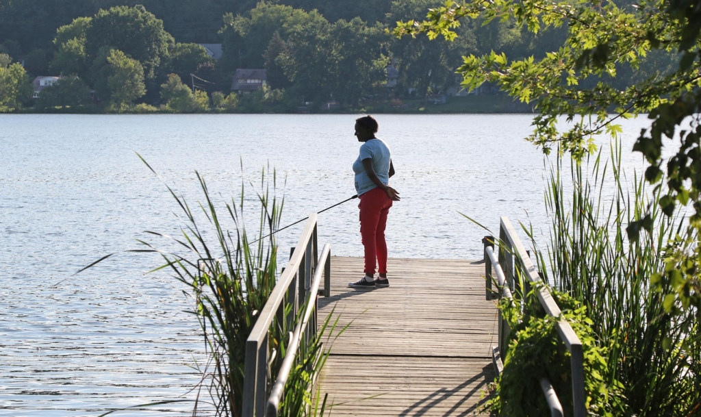 A woman fishing off of a wooden dock.