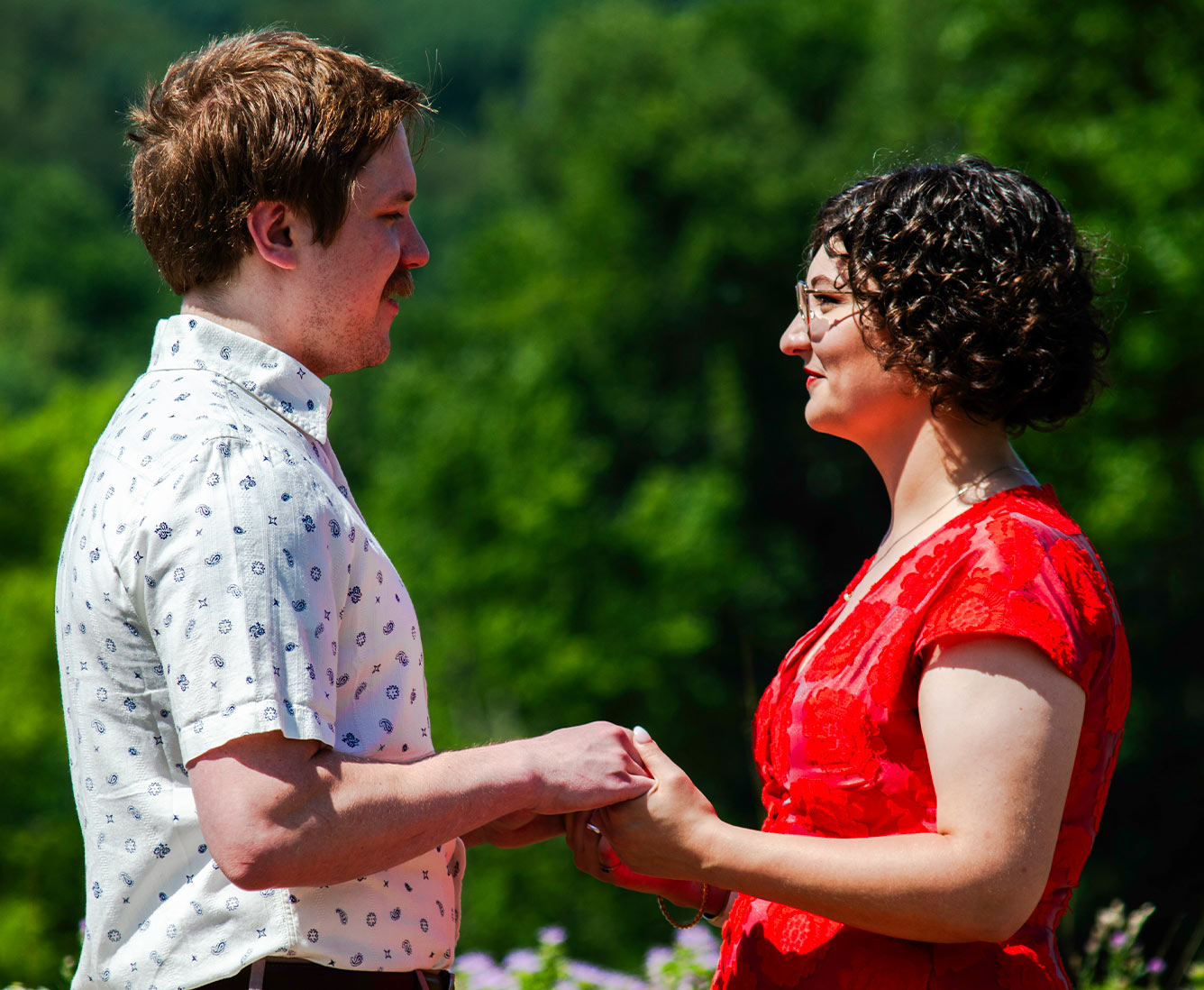 A man and woman hold hands while looking at each other.